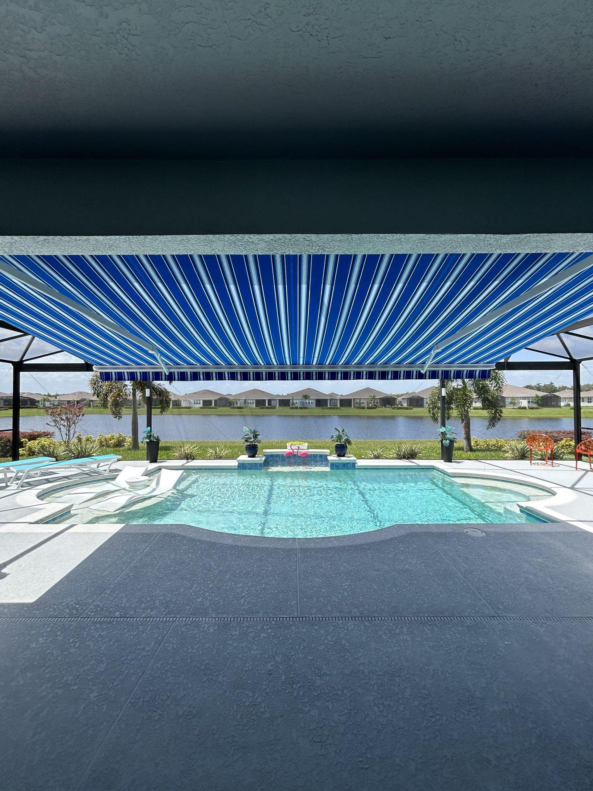 blue white striped motorized shade awning over pool